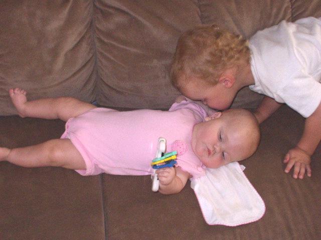 Elijah is giving Mary kisses. I think Mary was just trying to figure out how to get the toy in her mouth.